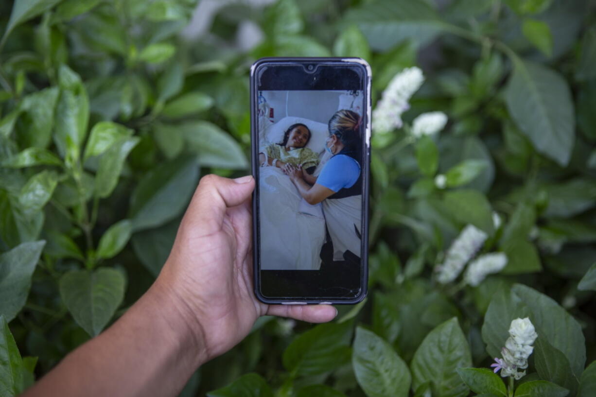 Mynor Cardona shows a photo on his cellphone of her daughter, Yenifer Yulisa Cardona Tom?s, at the hospital while receiving a visit, in Guatemala City, Monday, July 4, 2022. Yenifer Yulisa Cardona Tom?s is one of the survivors of the more than 50 migrants who were found dead inside a tractor-trailer near San Antonio, Texas.