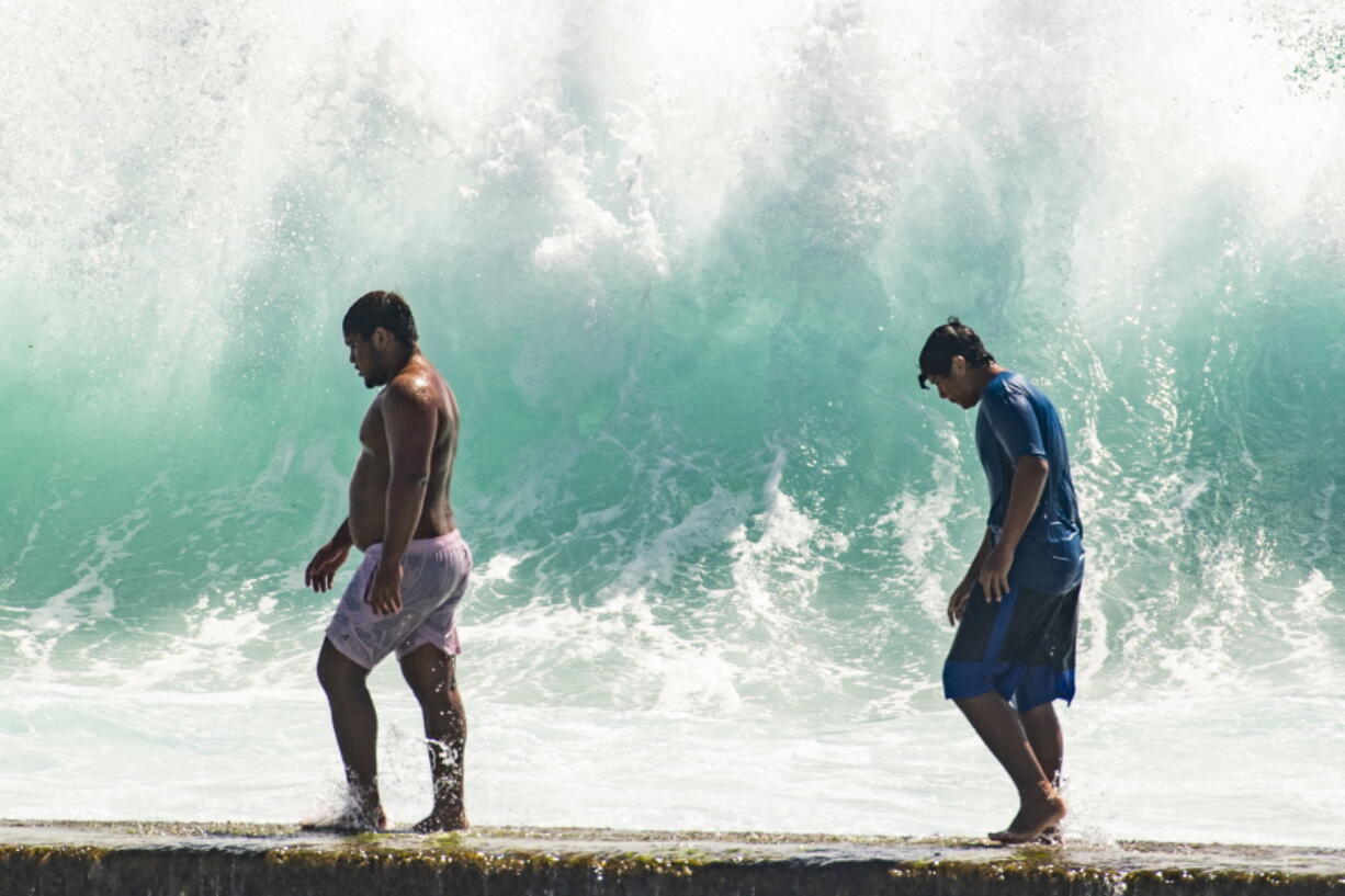 People walk in front of the high surf near Kapahulu Groin (Waikiki Wall) in Waikiki, Hawaii, Sunday, July 17, 2022. (Craig T.
