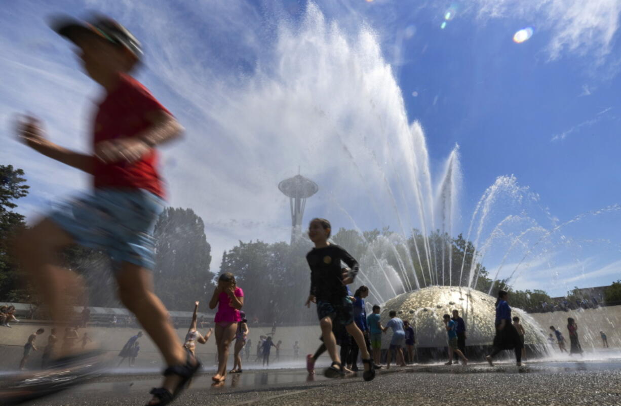 The International Fountain at Seattle Center is packed with children as they run from the water that is showering on them Wednesday, July 27, 2022 in Seattle. (Ellen M.