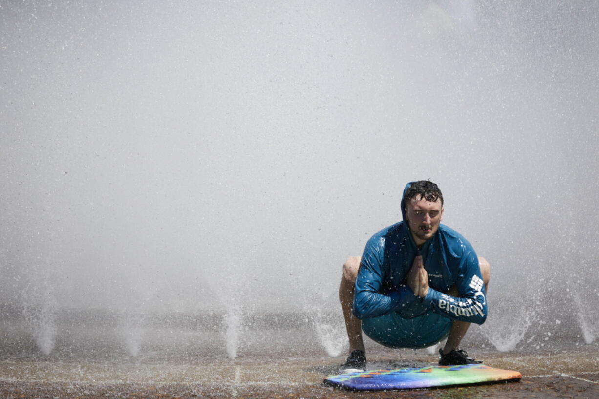 Jesse Moore cools off in the Salmon Street Springs fountain in Portland, Ore., Tuesday, July 26, 2022. Temperatures are expected to top 100 degrees F (37.8 C) on Tuesday and wide swaths of western Oregon and Washington are predicted to be well above historic averages throughout the week.