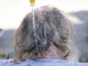 Maggy Johnston, ARCHES outreach coordinator, squeezes water on a man's head during a heat wave with temperatures reaching 100 degrees in Salem, Ore., Tuesday, July 26, 2022.