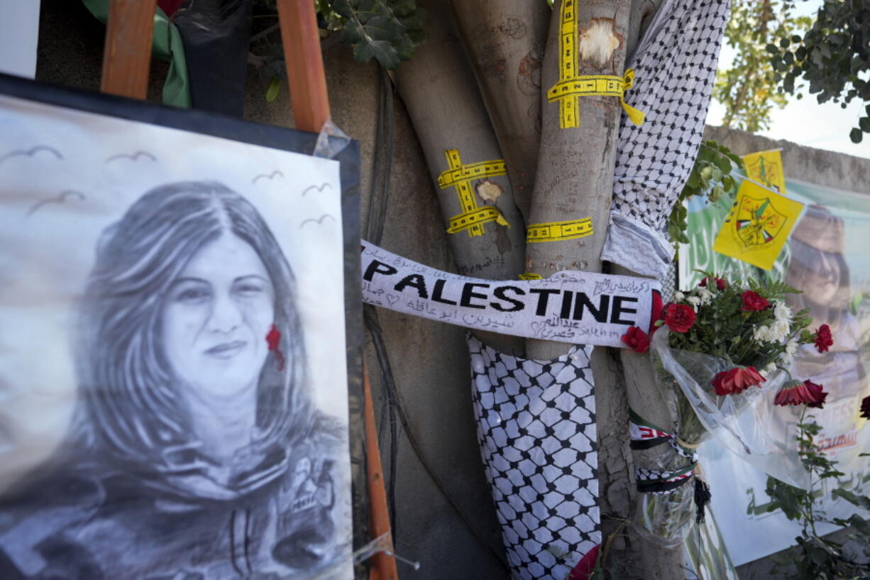 Yellow tape marks bullet holes on a tree and a portrait and flowers create a makeshift memorial on o May 19, 2022, at the site where Palestinian-American Al-Jazeera journalist Shireen Abu Akleh was shot and killed in the West Bank city of Jenin. The Palestinian Authority on Saturday, July 2, 2022, said it has given the bullet that killed Al Jazeera journalist Shireen Abu Akleh to American forensic experts, taking a step toward resolving a standoff with Israel over the investigation into her death.