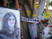 Yellow tape marks bullet holes on a tree and a portrait and flowers create a makeshift memorial on o May 19, 2022, at the site where Palestinian-American Al-Jazeera journalist Shireen Abu Akleh was shot and killed in the West Bank city of Jenin. The Palestinian Authority on Saturday, July 2, 2022, said it has given the bullet that killed Al Jazeera journalist Shireen Abu Akleh to American forensic experts, taking a step toward resolving a standoff with Israel over the investigation into her death.