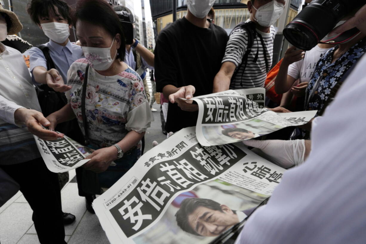 An employee distributes extra editions of the Yomiuri Shimbun newspaper reporting on Japan's former Prime Minister Shinzo Abe was shot, Friday, July 8, 2022, in Tokyo.