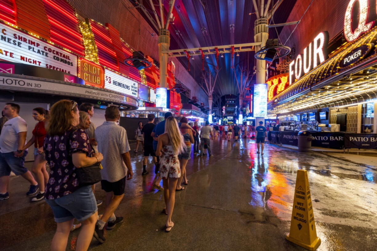 People navigate the rainy walkways as some power is out at the Fremont Street Experience as a powerful storm moves through the area on Thursday, July 28, 2022, in Las Vegas. (L.E.