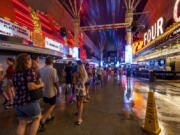 People navigate the rainy walkways as some power is out at the Fremont Street Experience as a powerful storm moves through the area on Thursday, July 28, 2022, in Las Vegas. (L.E.