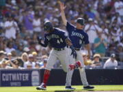 Seattle Mariners' Julio Rodriguez, left, reacts with third base coach Manny Acta after hitting a two-run home run during the fourth inning of a baseball game against the San Diego Padres, Monday, July 4, 2022, in San Diego.