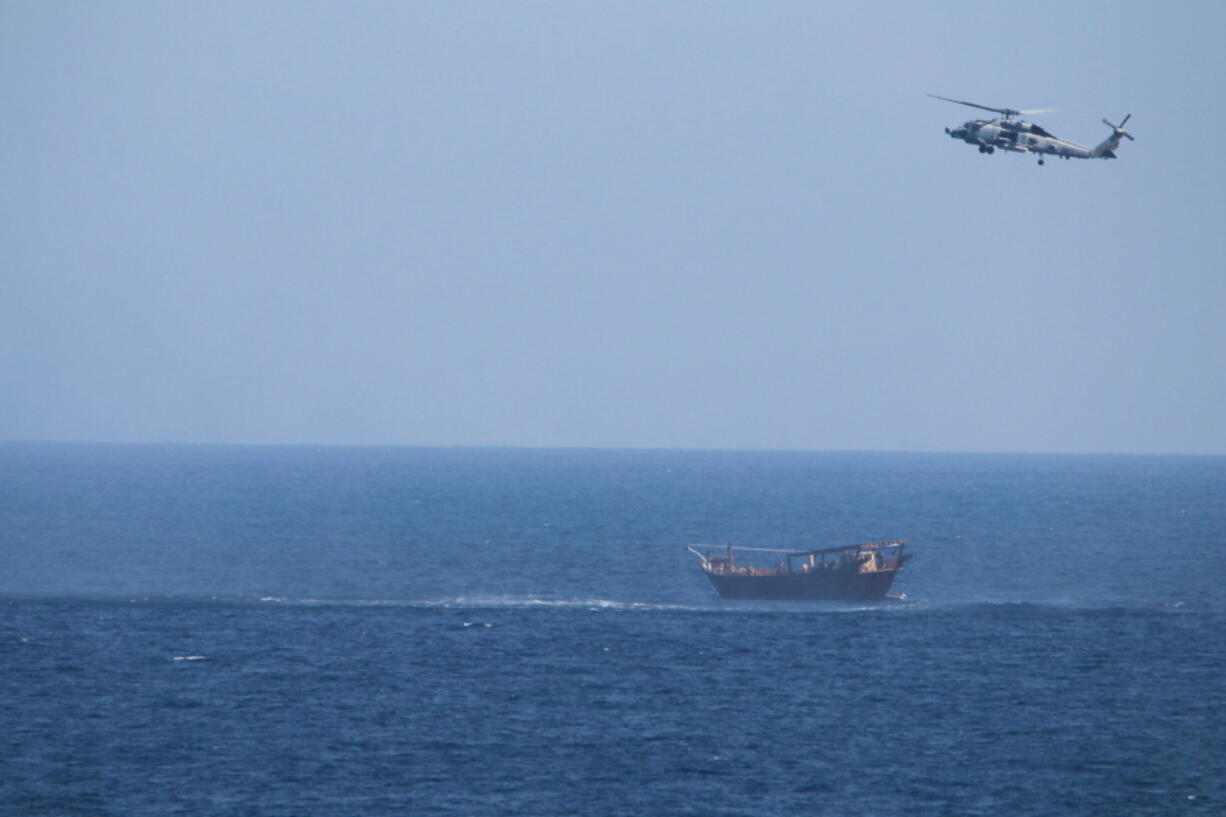 FILE - A U.S. Navy Seahawk helicopter flies over a stateless dhow later found to be carrying a hidden arms shipment in the Arabian Sea, May 6, 2021. The U.S. Navy's Mideast-based 5th Fleet will begin Tuesday, July 5, 2022, to offer rewards for information that could help sailors intercept weapons, drugs and other illicit shipments across the region. The program launches against the backdrop of tensions over Iran's nuclear program and Tehran's arming of Yemen's Houthi rebels. (U.S.