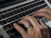 FILE- In this June 19, 2017, file photo, a person types on a laptop keyboard in North Andover, Mass.  The availability of remote work has increased significantly in recent years, giving rise to the ability for telecommuters to buck travel norms. Remote work has blurred the line between business and personal travel, affording workers the flexibility to extend trips to fly on cheaper days.