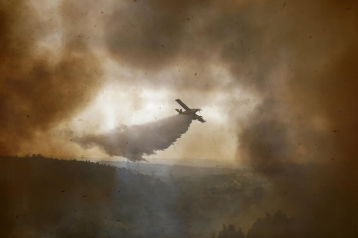 A firefighting airplane drops its load on a forest fire raging in the village of Casal da Quinta, outside Leiria, central Portugal, Tuesday, July 12, 2022. Hundreds of firefighters in Portugal continue to battle fires in the center of the country that forced the evacuation of dozens of people from their homes mostly in villages around Santarem, Leiria and Pombal.