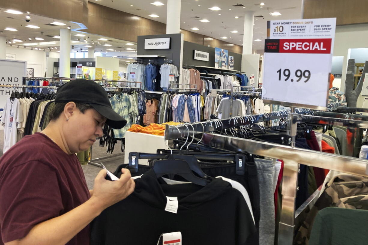 FILE - A customer checks price tags while shopping at a retail store in Schaumburg, Ill., Thursday, June 30, 2022. Consumers picked up their spending in June from May despite surging prices in gas and food. U.S. retail sales rose 1% last month, from a revised decline of 0.1 % in May, the Commerce Department said Friday, July 15, 2022. (AP Photo/Nam Y.