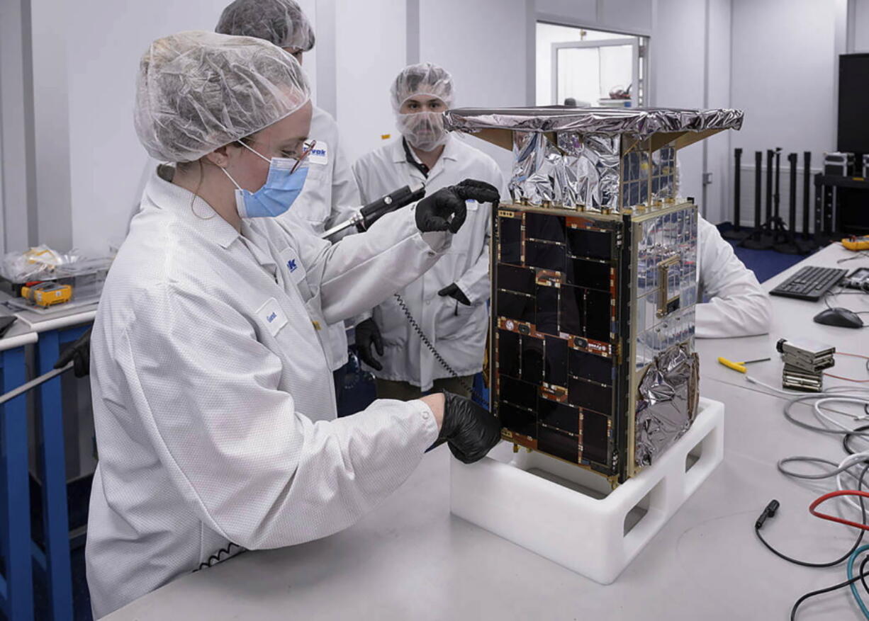 Rebecca Rogers, systems engineer, left, takes dimension measurements of the CAPSTONE spacecraft in April 2022, at Tyvak Nano-Satellite Systems, Inc., in Irvine, Calif. NASA said Tuesday, July 5,  that it has lost contact with a $32.7 million spacecraft headed to moon to test out a lopsided lunar orbit, but agency engineers are hopeful they can fix the problem.