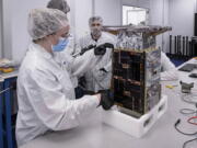 Rebecca Rogers, systems engineer, left, takes dimension measurements of the CAPSTONE spacecraft in April 2022, at Tyvak Nano-Satellite Systems, Inc., in Irvine, Calif. NASA said Tuesday, July 5,  that it has lost contact with a $32.7 million spacecraft headed to moon to test out a lopsided lunar orbit, but agency engineers are hopeful they can fix the problem.