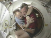 FILE - Shuttle Commander Terrence Wilcutt, right, and Mir Commander Anatoly Solovyev, left, hug after opening the hatches between the space shuttle Endeavour and the Russian Space station Mir Saturday, Jan. 24, 1998 in this image from television. Russia will opt out of the International Space Station after 2024 and focus on building its own orbiting outpost, the country's newly appointed space chief said Tuesday, July 26, 2022.