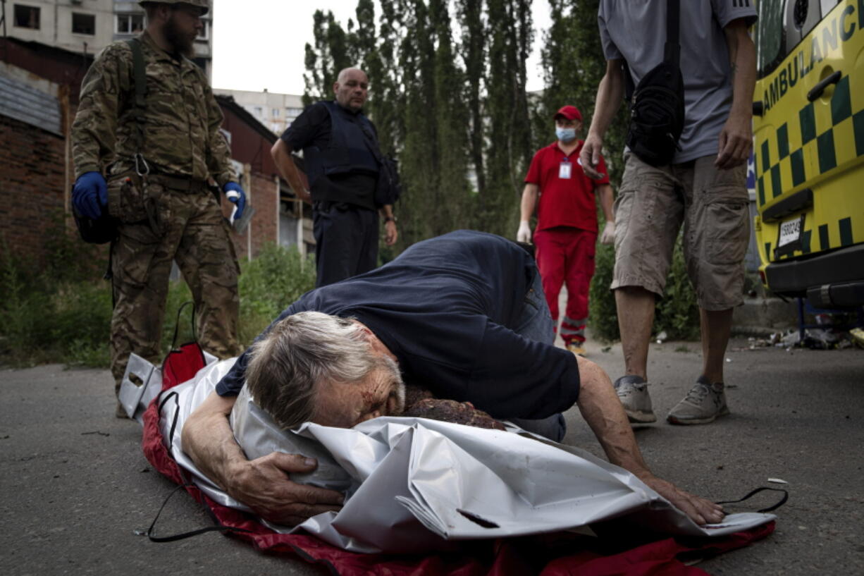 Viktor Kolesnik cries on a body of his wife Natalia Kolesnik, who was killed during a Russian bombardment at a residential neighborhood in Kharkiv, Ukraine, on Thursday, July 7, 2022.