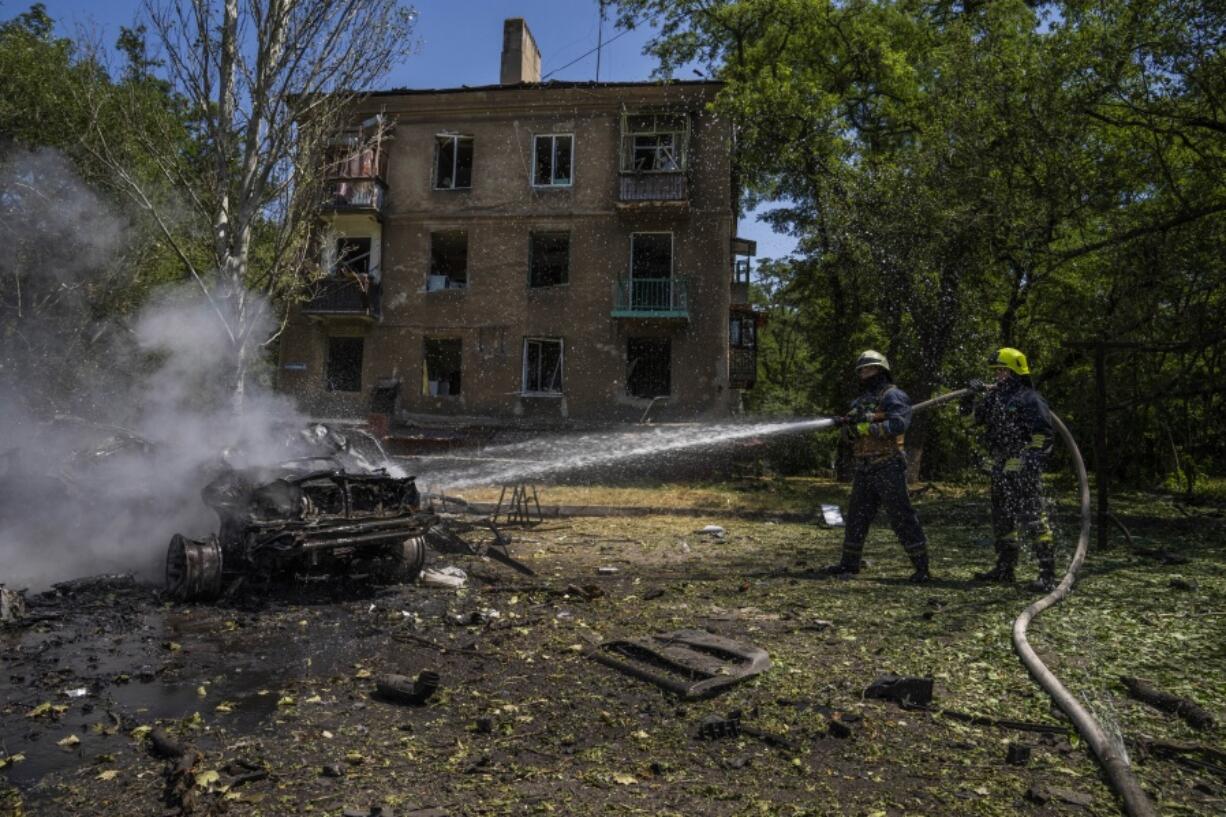 Firefighters hose down a burning car after a strike hit a residential area, in Kramatorsk, Donetsk region, eastern Ukraine, Thursday, July 7, 2022.