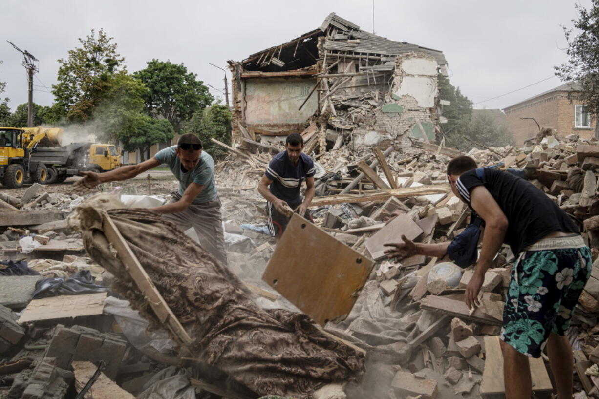 People search for documents belonging to their injured friend in the debris of a destroyed apartment house after Russian shelling in a residential area of Chuhuiv, Kharkiv region, Ukraine, on Saturday.