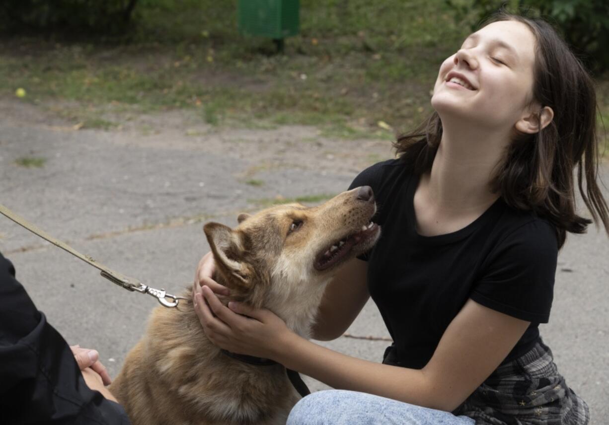 A girl plays with a dog in a pet shelter in Kyiv, Ukraine, Tuesday, July 19, 2022. Shellshocked family pets started roaming around Ukraine's capital with nowhere to go in the opening stages of Russia's war. Volunteers opened a shelter to take them in and try to find them new homes or at least some human companionship.