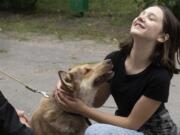 A girl plays with a dog in a pet shelter in Kyiv, Ukraine, Tuesday, July 19, 2022. Shellshocked family pets started roaming around Ukraine's capital with nowhere to go in the opening stages of Russia's war. Volunteers opened a shelter to take them in and try to find them new homes or at least some human companionship.