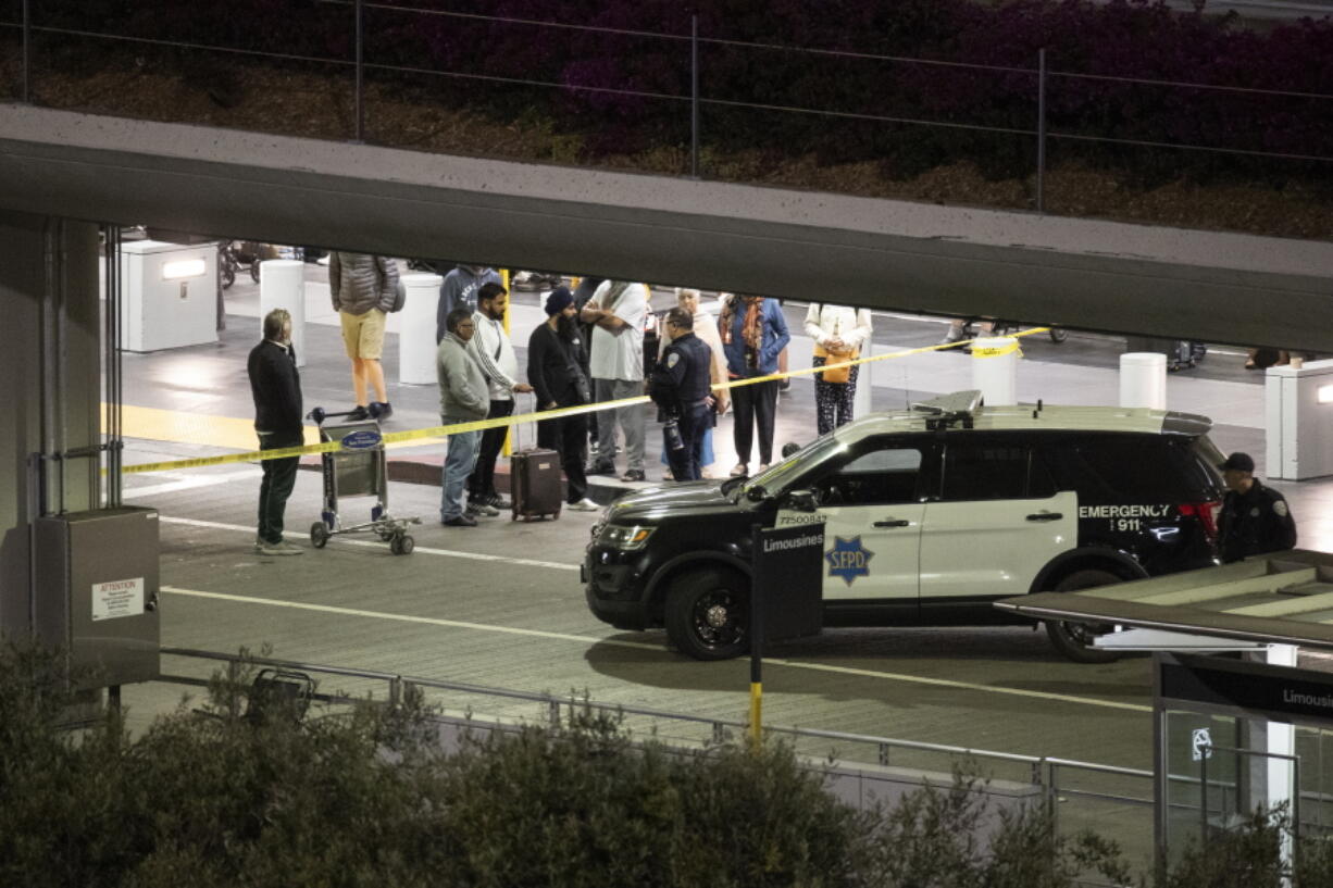 People gather by a police line at San Francisco International Airport after a reported bomb threat forced an evacuation of the International Terminal in San Francisco Friday, July 15, 2022. The San Francisco International Airport's international terminal was evacuated on Friday night due to a bomb threat and authorities found a potentially incendiary device, officials said.