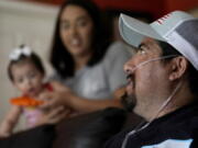 Freddy Fernandez sits with his fianc?, Vanessa Cruz, and their 8-month-old daughter, Mariana Fernandez in their home Friday, June 10, 2022, in Carthage, Mo. After contracting COVID-19 in August 2021, Fernandez spent months hooked up to a respirator and an ECMO machine before coming home in February 2022 to begin his long recovery from the disease.