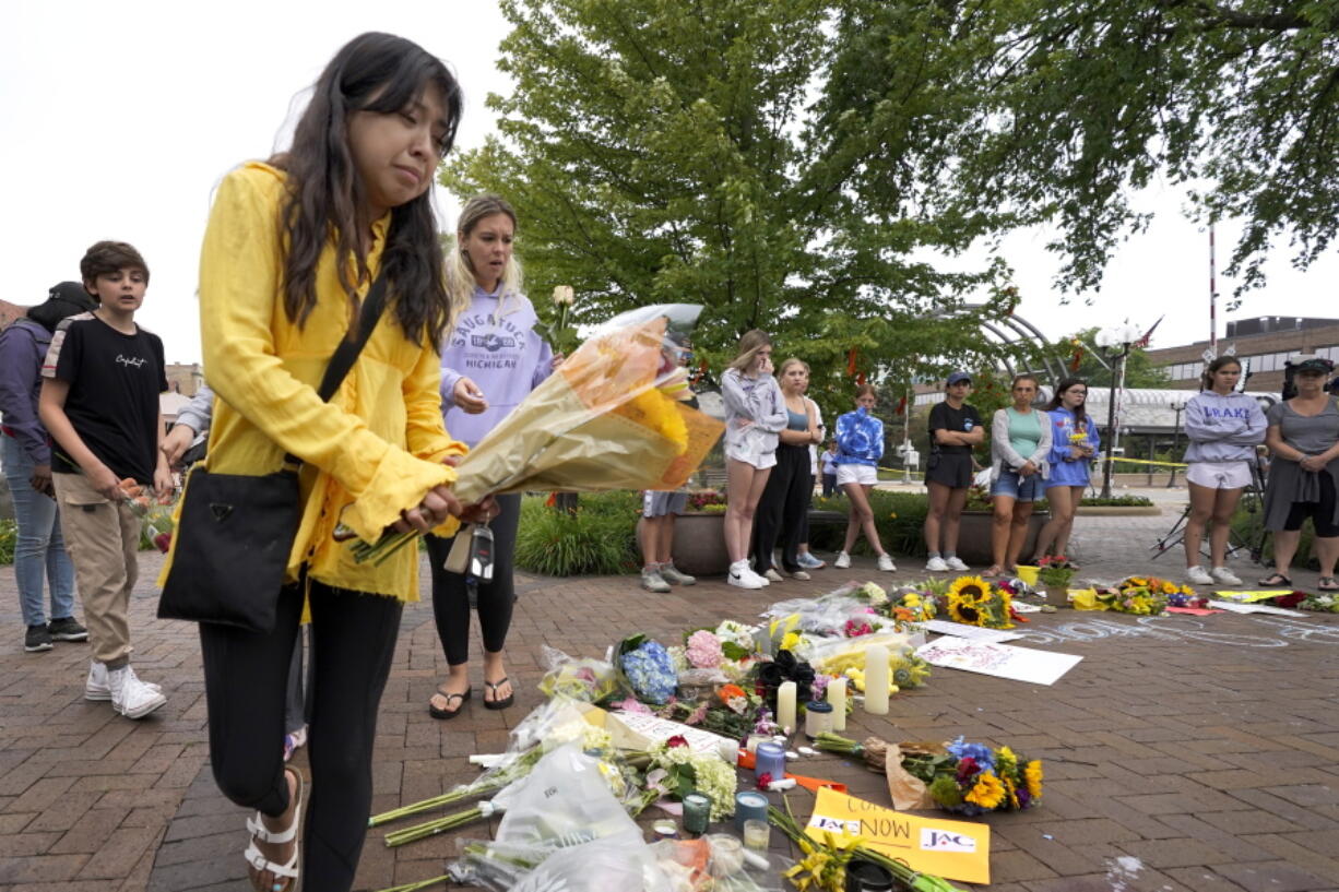 Yesenia Hernandez, granddaughter to Nicolas Toledo, who was killed during Monday's Highland Park., Ill., Fourth of July parade, brings flowers to a memorial for Toledo and six others who lost their lives in the mass shooting, Wednesday, July 6, 2022, in Highland Park.