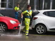 A worker sprays water in the street while a road sweeper walks behind her during hot weather in Madrid, Spain, Wednesday, July 20, 2022.