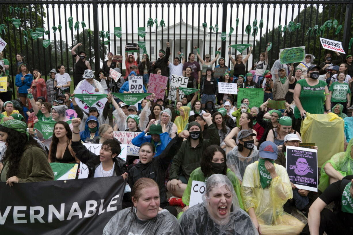 Abortion-rights demonstrators shout slogans after tying green flags to the fence of the White House during a protest to pressure the Biden administration to act and protect abortion rights, in Washington, Saturday, July 9, 2022.