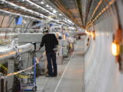 FILE - A technician works in the LHC (Large Hadron Collider) tunnel of the European Organization for Nuclear Research, CERN, during a press visit in Meyrin, near Geneva, Switzerland, Feb. 16, 2016. The physics lab that's home to the world's largest atom smasher announced on Tuesday, July 5, 2022 the observation of three new "exotic particles" that could provide clues about the force that binds subatomic particles together. The observation of a new type of pentaquark and the first duo of tetraquarks at CERN, the Geneva-area home to the LHC, offers a new angle to assess the so-called "strong force" that holds together the nuclei of atoms.