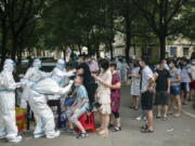 FILE - Residents line up to be tested for COVID-19 in Wuhan, central China's Hubei province on Aug. 3, 2021. Two new studies provide more evidence that the coronavirus pandemic originated in a Wuhan, China market where live animals were sold - further bolstering the theory that the virus emerged in the wild rather than escaping from a Chinese lab. The research was published online Tuesday, July 26, 2022, by the journal Science.