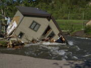 FILE - A house sits in Rock Creek after floodwaters washed away a road and a bridge in Red Lodge, Mont., on June 15, 2022. As cleanup from historic floods at Yellowstone National Park grinds on, climate experts and meteorologists say the gap between the destruction in the area and what was forecast underscores a troublesome trend tied to climate change: Modeling programs used to predict storms aren't keeping up with increasingly extreme weather.