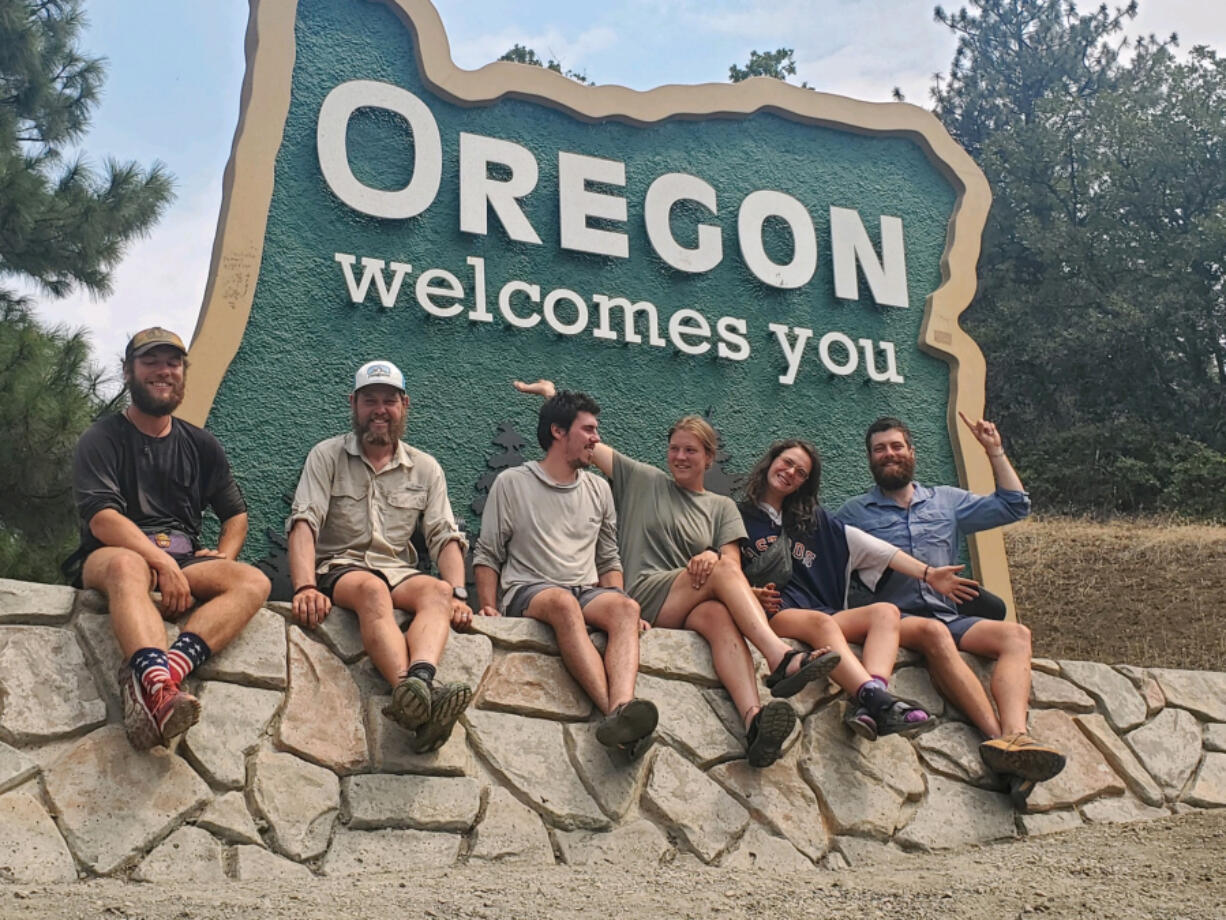 Pacific Crest Trail hikers pose in front of the Oregon Welcomes You sign after crossing into Oregon from California.