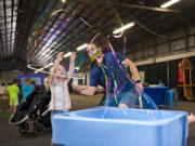 Zayla Tervo, 3, smiles from inside a large bubble made by her father, Bryce Tervo, while her brother, Elijah, 2, at right, watches Saturday at the Wild Science exhibit at the Clark County Fair. The bubble stations were popular attractions at the exhibit in the South Hall.