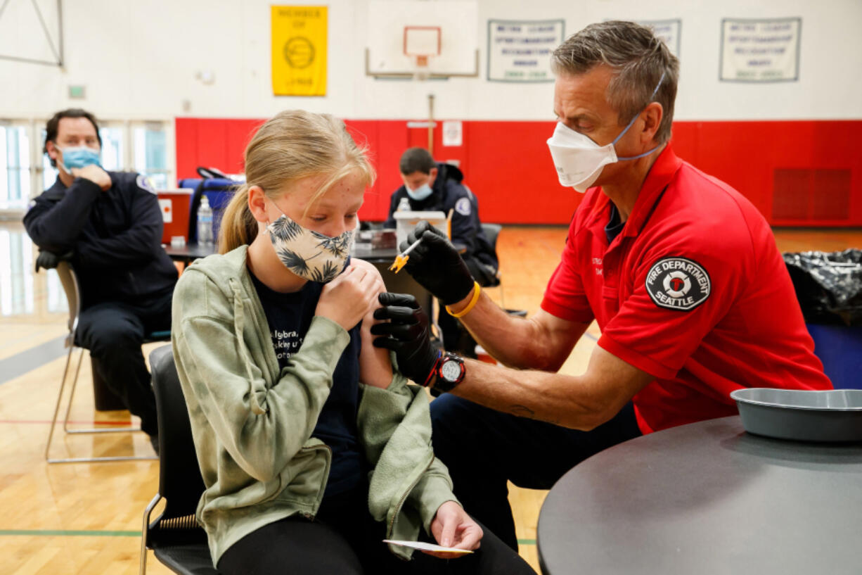 Seattle firefighter and EMT Garth Stroyan administers a COVID-19 vaccination for Asya Strounine, 13, at Nathan Hale High School in Seattle on June 10, 2021.