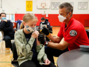 Seattle firefighter and EMT Garth Stroyan administers a COVID-19 vaccination for Asya Strounine, 13, at Nathan Hale High School in Seattle on June 10, 2021.
