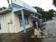 John Tweedy wades into the swift-moving floodwater surrounding his business as he inspects damage in the wake of Hurricane Matthew on October 8, 2016, in McClellanville, South Carolina.