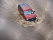 A pickup truck drives through one of the closed lanes on westbound Highway 94 just east of the northbound Interstate 805 due to flooding from the rain, Nov. 28, 2019, in San Diego.