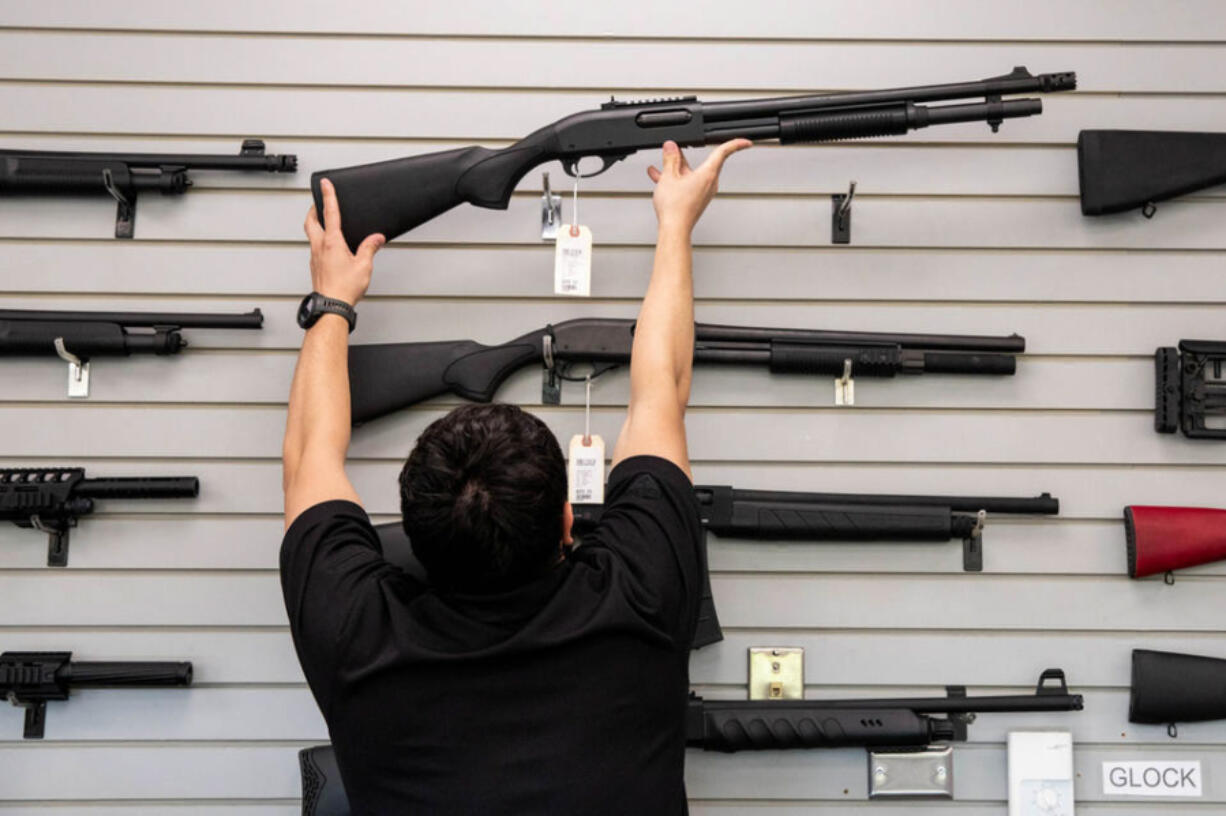 An employee puts back an Remington 870 shotgun for sale at Wade's Eastside Guns in Bellevue on Monday, Aug. 22, 2022.