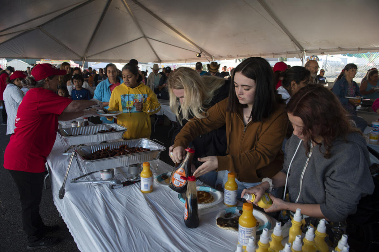 LEADOPTION Roommates Kalie Foster, left, Lindsey Califf and Crystal Brumitt prepare their pancakes during the free Fred Meyer breakfast at the Clark County Fairgrounds on Friday morning. The breakfast is held from 8 to 11 a.m. on the first day of the fair.