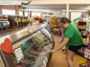 Owner Jenell Anderson, right, holds her daughter, Nora Einarson, 1, and adjusts a sign on a meat cooler at the Heisson Store in Battle Ground.