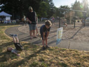 Emmett Reese, 7, and his brother, Cooper, 4, along with their parents, Alena and Spencer Reese of Vancouver, read "Bear Came Along" by Richard T. Morris one page at a time circling the playground at Hearthwood Park.