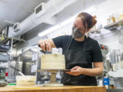 Karalee Tittle spreads cream cheese frosting on a carrot cake at Bleu Door Bakery in Vancouver's Uptown Village. Inflation has increased the price of baking goods like flour, eggs and butter.