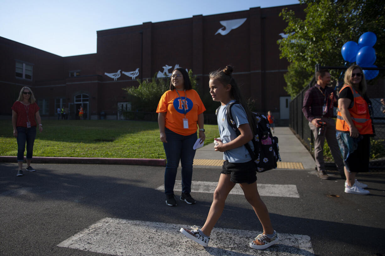 Union Ridge Elementary School second-grader Eylee Klug, 7, gets a warm welcome from teachers and staff as she arrives for the first day of school Wednesday morning. Wednesday was the first day of school for the Ridgefield School District, where a divide between district administration and the teachers union looms.