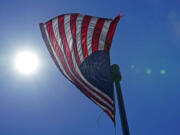 A U.S. flag flies with the sun in the background in downtown Seattle.  (AP Photo/Ted S.