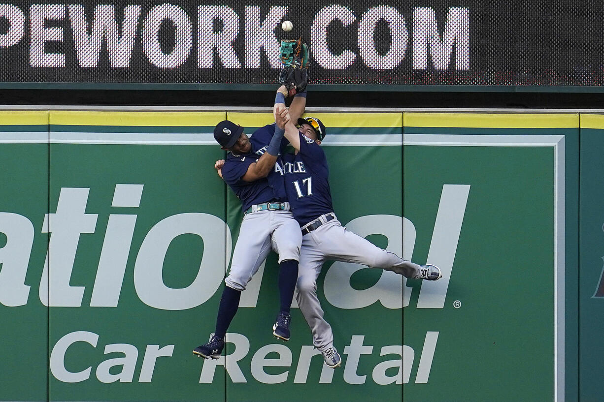 Seattle Mariners center fielder Julio Rodriguez, left, and right fielder Mitch Haniger collide at the wall while trying to catch a fly ball from Los Angeles Angels' Luis Rengifo during the first inning of a baseball game Monday, Aug. 15, 2022, in Anaheim, Calif. Rengifo was awarded a solo home run on the play.