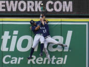 Seattle Mariners center fielder Julio Rodriguez, left, and right fielder Mitch Haniger collide at the wall while trying to catch a fly ball from Los Angeles Angels' Luis Rengifo during the first inning of a baseball game Monday, Aug. 15, 2022, in Anaheim, Calif. Rengifo was awarded a solo home run on the play.