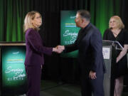 Washington Secretary of State Steve Hobbs, second from right, a Democrat, and Pierce County Auditor Julie Anderson, left, running as a nonpartisan, shake hands after taking part in a debate, Wednesday, Aug. 17, 2022, in Olympia, Wash., as moderator Melissa Santos, right, of Axios Local, looks on. Hobbs and Anderson are seeking to fill the remaining two years of the term of Republican Secretary of State Kim Wyman, who left to take a key election security job in the Biden administration. (AP Photo/Ted S.