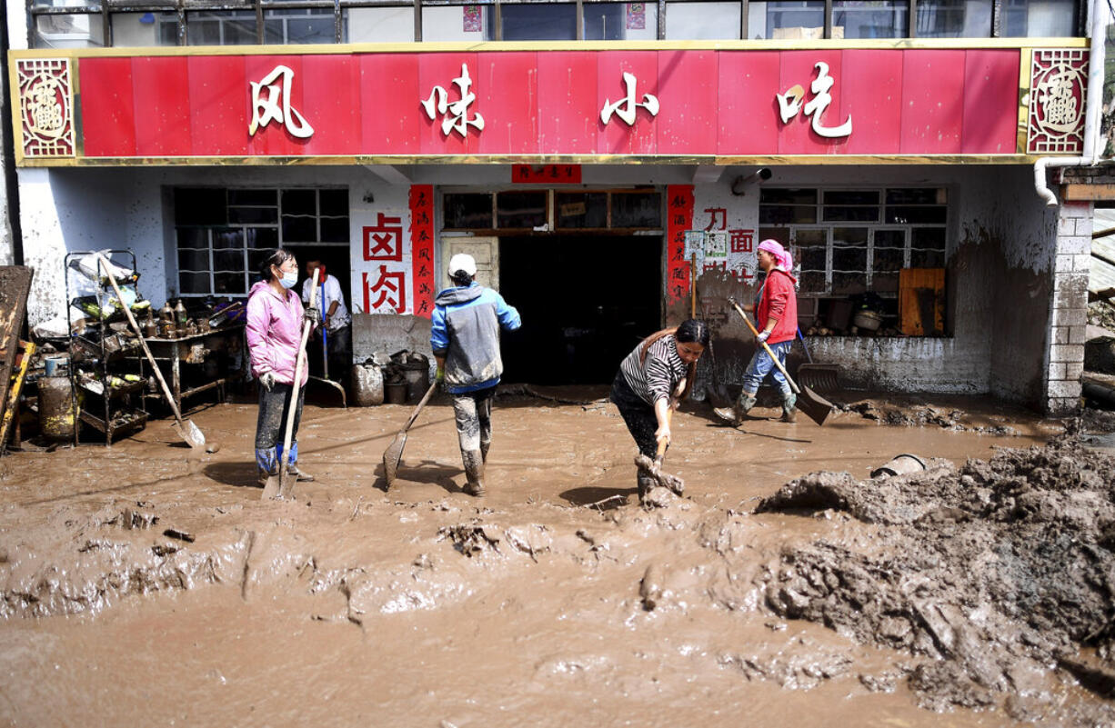 In this photo released by Xinhua News Agency, residents clear sludge from their property in the aftermath of floods in Qingshan Township of Datong Hui and Tu Autonomous County in northwest China's Qinghai Province on Thursday, Aug. 18, 2022. A sudden rainstorm in western China triggered a landslide that diverted a river and caused flash flooding in populated areas, killing some and leaving others missing, Chinese state media said Thursday.