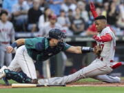 Seattle Mariners catcher Cal Raleigh tags out Los Angeles Angels' Magneuris Sierra at home plate after Sierra attempted to stretch a triple to an inside-the-park home run during the second inning of a baseball game Friday, Aug. 5, 2022, in Seattle.