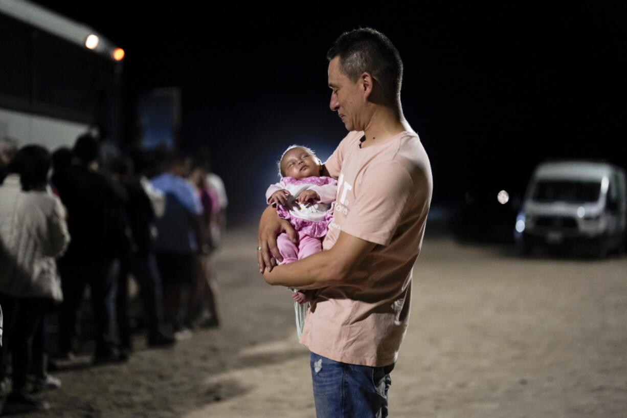 A migrant man from Colombia holds his baby daughter after crossing into the United States near the end of a border wall Tuesday, Aug. 23, 2022, near Yuma, Ariz. A border wall with Mexico isn't the issue it was during Donald Trump's presidency but plans for more barriers in Yuma, Ariz., is a reminder of obstacles that the federal government always faces: difficulty working on tribal lands and private property.